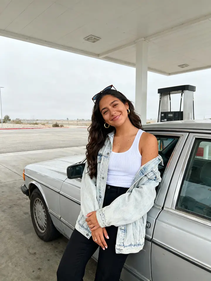Original phone photo of a woman leaning on a car at a gas station
